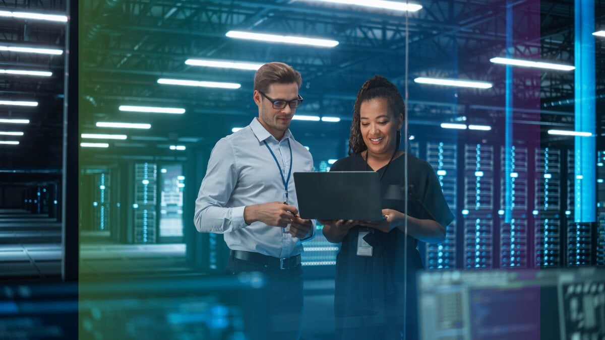 Two data center professionals reviewing infrastructure plans on a laptop
